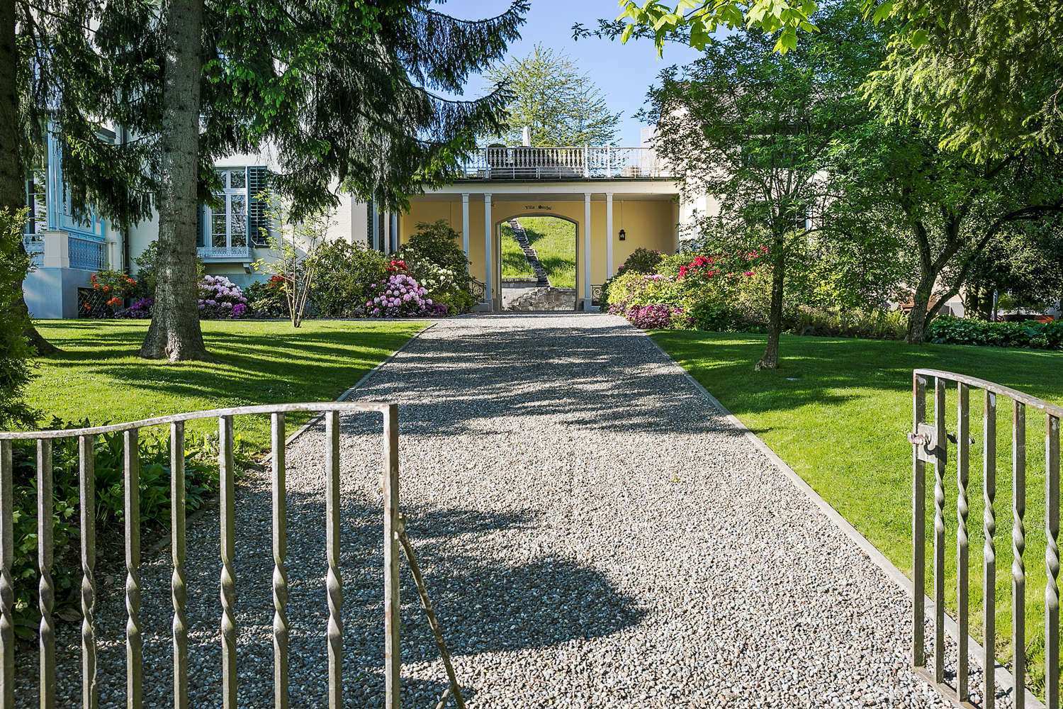 Die Umgebungsgestaltung der eindrücklichen Villa am Zürichsee wird von mächtigen Bäumen dominiert.